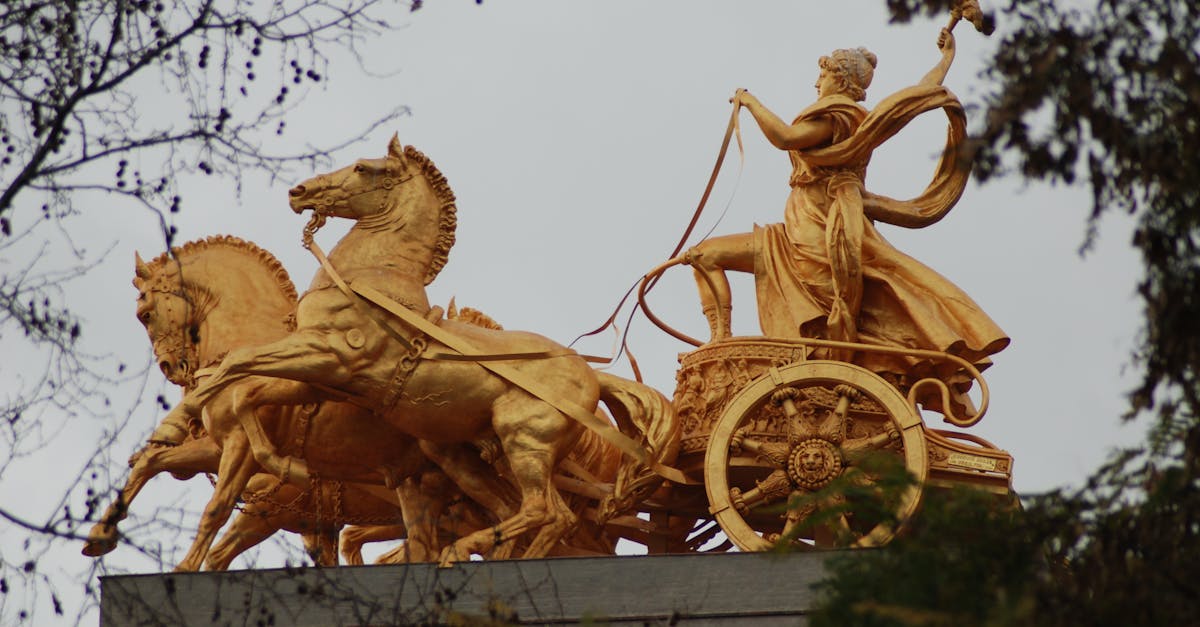A stunning golden statue of a chariot and horses captured in an outdoor setting during autumn.