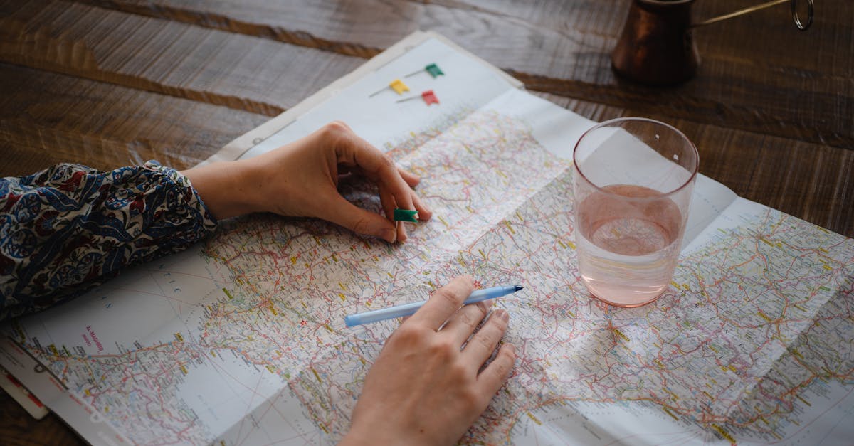 A woman places a pin on a map while planning a trip, with a glass of water nearby.