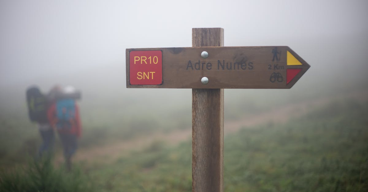 Trail sign marking the path to Adre Nunes in Portugal, captured on a foggy day.