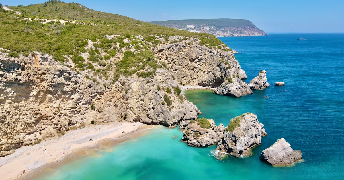 Breathtaking aerial view of Praia do Ribeiro do Cavalo’s rocky coastline and turquoise waters in Portugal.