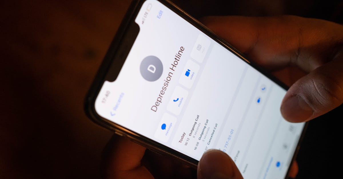 A close-up of a hand holding a smartphone displaying a depression hotline contact.