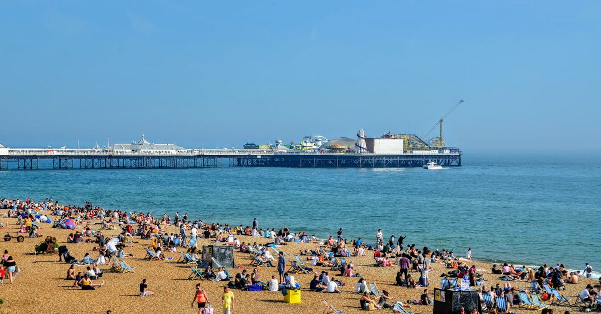 People enjoying a sunny day on Brighton Beach with a view of the iconic pier.