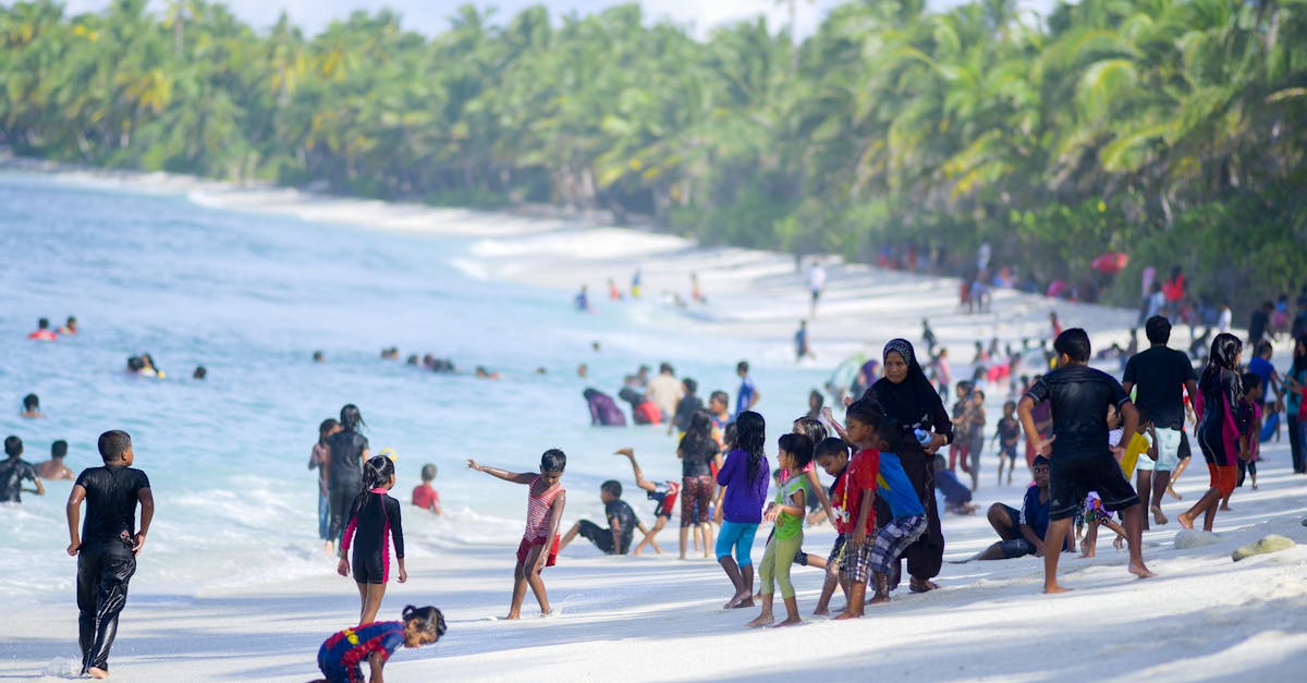 A lively beach with families and children enjoying a sunny day by the sea.