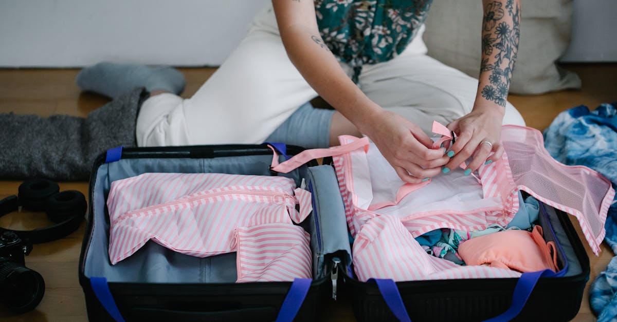 A woman packing her travel suitcase on the floor indoors, preparing for a trip.