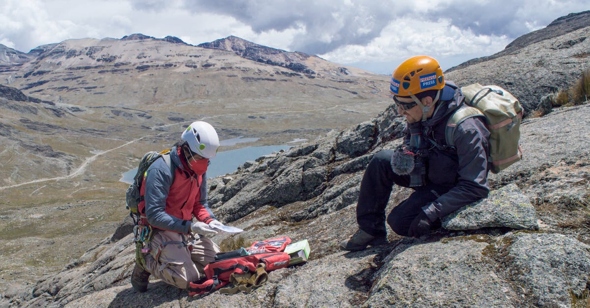 Two climbers navigate the rugged mountainous terrain using maps and equipment.