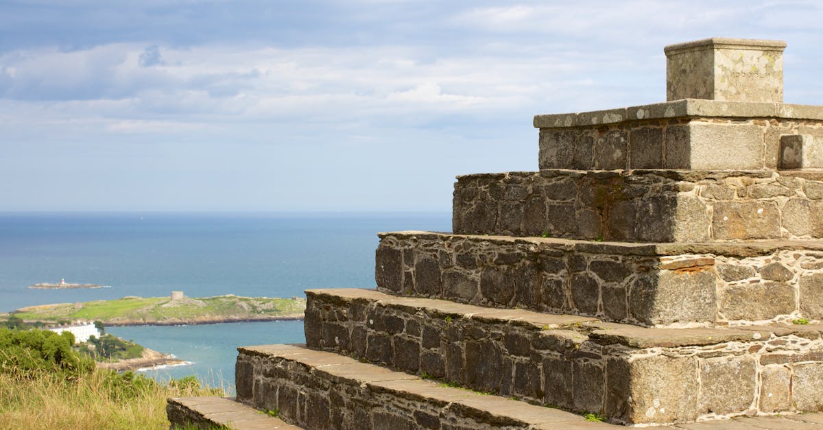 Stone step structure on a hilltop with a scenic ocean view under a clear sky.